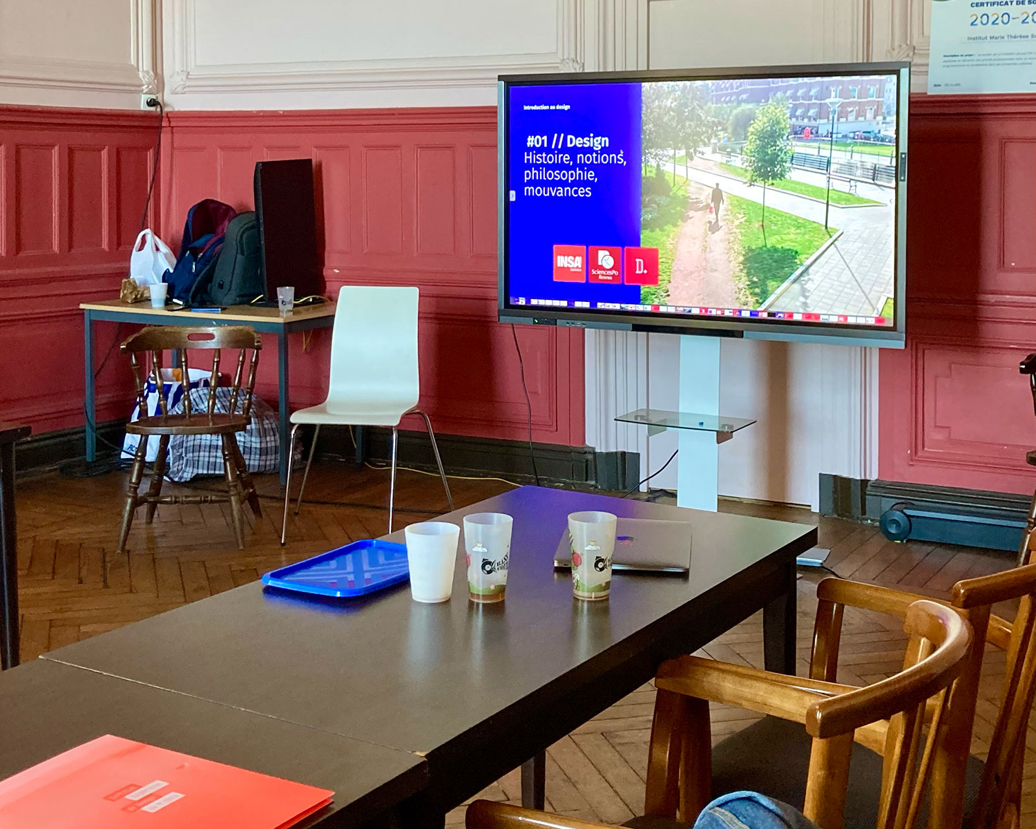 Salle préparée pour une présentation, écran affichant « Design : histoire, notions, philosophie, mouvances »